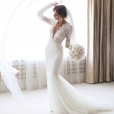 a woman in a wedding dress standing next to a window