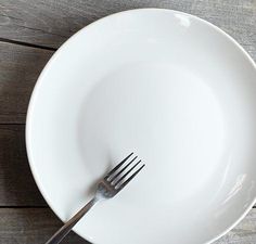 a white plate with a fork and knife in it on a wooden table top,