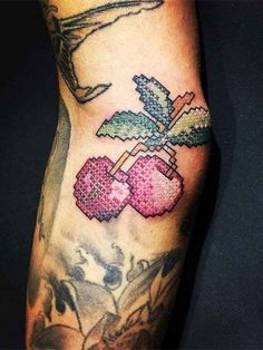 a person with a tattoo on their arm holding a cupcake and cherries in it