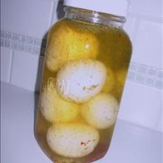 a jar filled with pickles sitting on top of a counter next to a tiled wall