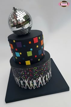 a three tiered cake decorated with disco balls and people dancing on the bottom layer