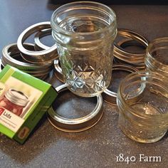 there are many mason jars and lids on the counter top, including one with an empty box