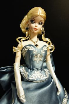 a barbie doll wearing a blue dress and white gloves with gold trimmings on her head