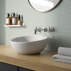 a white bowl sink sitting on top of a wooden counter next to a bathroom mirror