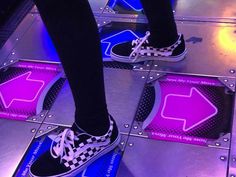 the legs of a person wearing black and white checkered shoes on a metal platform