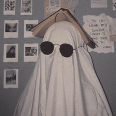 a white ghost with sunglasses on it's head is hanging from a wall covered in pictures