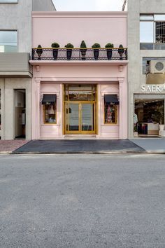 an empty street in front of a pink building with gold trimmings and windows