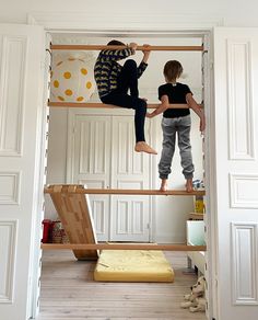 two children are climbing up the ladders in their room, one boy is on top of the bunk bed