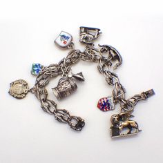 "Vintage ornate 830 silver chain bracelet decorated with 8 figural dangle charms, representing different European destinations. Some charms are accented with colorful enamel, one charm is silver-plated. This lovely bracelet is 7 1/2\" long, weighing 46.8 grams or 1.5 ozs Troy. EA3729" Antique Metal Bracelet With Charms, Enamel Charms Bracelet, Vintage Enamel Charms Jewelry, Collectible Metal Charm Bracelet With Lobster Clasp, Silver Charms Jewelry Souvenir, Metal Charms With Lobster Clasp For Collectors, Collectible Vintage Charm Metal Bracelet, Collectible Vintage Charm Costume Bracelet, Silver Metal Chain Bracelet With Dangling Charms