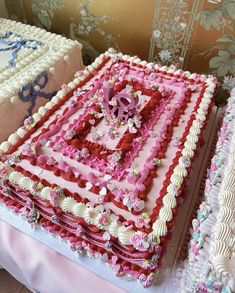 two large cakes sitting on top of a table covered in frosting and pink icing