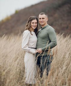 a man and woman are standing in the tall grass with their arms around each other