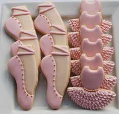 decorated cookies in the shape of ballet shoes on a white plate with pink icing