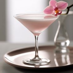 a pink drink in a martini glass on a tray