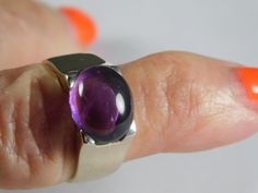 Jelly Bean Amethyst Cabochon Ring in !4K white gold. The ring features an oval amethyst that measures 12X10mm and by formula is 4.5 carats. The gemstone is set East to West and in a square top white gold mounting. The ring is solid 14K white gold and has a very good gold weight of 5.3 grams of solid gold. Currently a size 8, the ring can be sized up or down as needed. The ring is 10mm wide and tapers down to 4.85mm at bottom with a rise off of the finger of 7.29mm. Note that 6mm is approximately Modern Oval Amethyst Ring With Polished Finish, Oval Amethyst Ring For Gift, Modern Oval Amethyst Ring For Gift, Modern Oval Amethyst Ring Gift, Square Top, Jelly Bean, Cabochon Ring, Alternative Engagement Rings, Aquamarine Rings