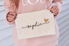 a woman holding a personalized pouch with the word sophiia written on it