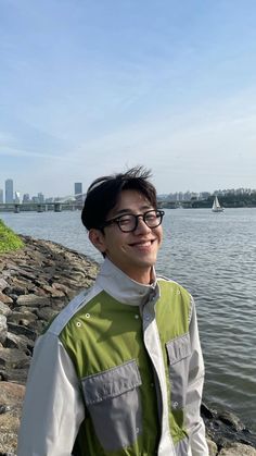 a man wearing glasses standing next to the water