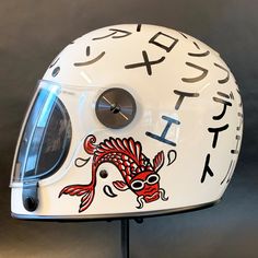 a helmet with japanese writing on it and a fish design painted on the front side