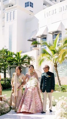 a bride and groom walking down the aisle at their wedding ceremony in front of a hotel