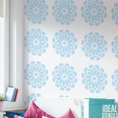 a white couch sitting under a window next to a blue and white wallpaper covered in flowers