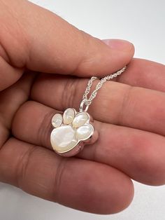 This is the perfect gift and a unique way to carry your loved ones close to your heart. This jewelry is designed to hold a small portion of ashes, hair, or dried ceremonial flowers. ❤️Size: 3/4"w x 3/4"h ❤️Holds Cremains: YES ❤️FREE Personalization: message can be engraved on the back of the pendant; 12 characters maximum. ❤️Material:  genuine 925 sterling silver ❤️Included in the package:18" matching silver chain,gift box, filling funnel kit; ❤️ Care Instructions: Though the materials used is made of sterling silver, I recommend you to not sleep, swim, or spray chemicals (i.e. perfumes, lotions, or body spray) on to the necklace to preserve its longevity. Please follow these tips to preserve the longevity of the necklace. To clean, it is best to use a soft microfiber cloth to clean the je Paw Pendant, Ashes Necklace, Urn Pendant, Urn Jewelry, Pearl Stone, Memorial Jewelry, Pendant Silver, Body Spray, Mother Of Pearl