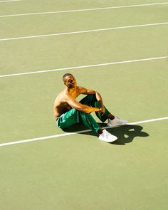 a man sitting on top of a tennis court holding a racquet in his hand