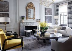 a living room filled with furniture and a fire place under a mirror on the wall