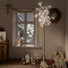 a christmas tree in front of a window with lights and presents on the floor next to it