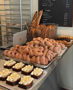 doughnuts and pastries are on display in front of a chalkboard with writing