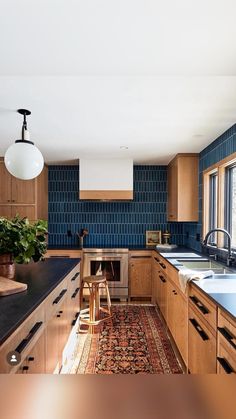 a kitchen with wooden cabinets and blue tile backsplash, an area rug on the floor