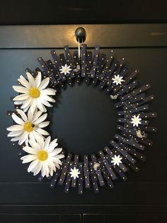 a wreath with white daisies is hanging on the door to display it's decorations