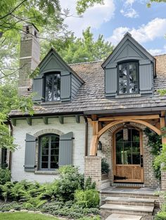 a house with gray shutters and stone steps leading up to the front door is surrounded by greenery