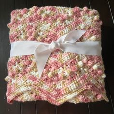 a crocheted blanket with a white bow on it