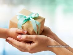 two hands holding a wrapped gift box with a green bow on it's ribbon