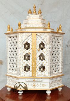 an ornate white and gold clock on top of a wooden table