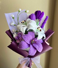 a bouquet of purple and white flowers in someone's hand