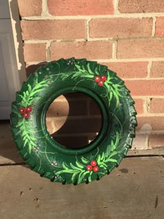 a green painted tire sitting in front of a brick wall with red berries on it