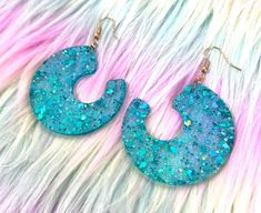 These far-out glitter blue resin earrings are perfect for your next festival or event! The deets: -Main material: Resin -Color option: Blue w/ glitter -Other materials: Silicone, Plastic, Metal -Rubber & Metal backing included -Due to its handcrafted nature, all jewelry can slightly vary in size & color -Please avoid bending the resin; it is durable, but handle with care -Although returns and exchanges are not accepted, please reach out if you have issues with your order Please make sure to doub Jewelry Homemade, Diy Resin Projects, Earrings Resin, Resin Projects, Sparkle Earrings, Homemade Jewelry, Diy Resin, Resin Earrings, Fun Earrings