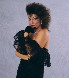 a woman in a black dress posing with her hands on her face and wearing gloves