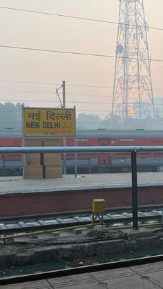 an empty train track with a sign in the background that says new delhi on it