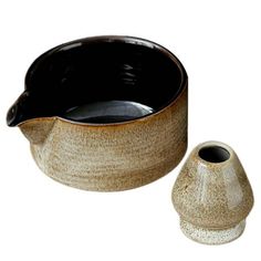 a black and white ceramic bowl next to a small brown pottery vase on a white background