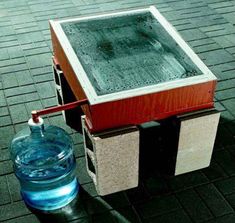 a water container with a handle attached to it sitting on the ground next to a blue bottle