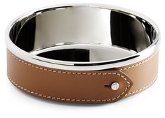 a brown leather dog bowl with white stitching on the side and a silver plate in the center