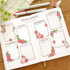 an open planner with strawberries on it next to some flowers and two pencils