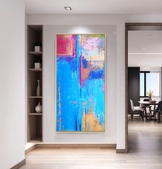 an abstract painting hangs on the wall next to a dining room table and bookshelf