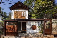 the house is made out of wood and has a white facade with brown shutters