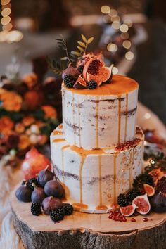 a three tiered cake with figs and berries on top