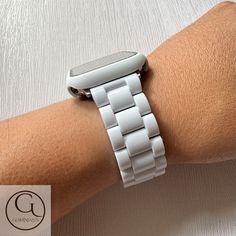 a person wearing a white watch on their arm with an apple watch in the background