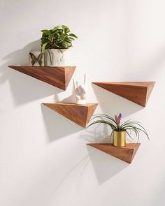 three wooden shelves with plants on them against a white wall, one has a potted plant and the other has a gold vase