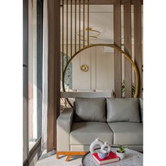 a living room with a couch, coffee table and round mirror in the corner on the wall