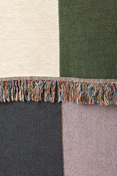 several different colors of fabric with fringes on top of each other, including green and brown